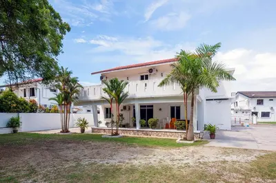 a white house with palm trees in front of it at Seaside Private Bungalow, Tg Bungah in Tanjung Bungah