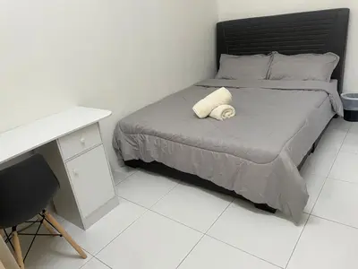 a bedroom with a bed with a desk and a white floor at ZaraVip homestay in Lahat