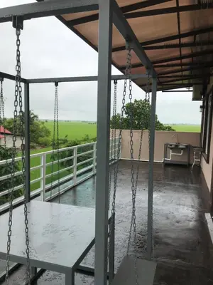 a porch with swings and a view of a field at Bendang Homes - Sekinchan Homestay in Kampong Sungai Leman