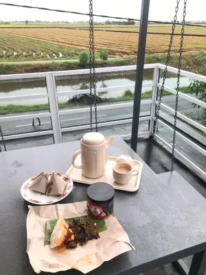 a table with a plate of food and a cup of coffee at Bendang Homes - Sekinchan Homestay in Kampong Sungai Leman