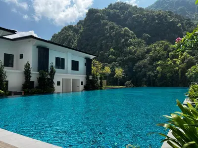 a swimming pool in front of a house with mountains in the background at Ipoh Peaceful Onsen studio Lost World Tambun in Tambun