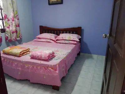 a bedroom with a pink bed with pink sheets and pillows at Idaman guesthouse Malay FAMILY ONLY in Kubang Semang
