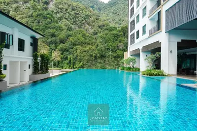 a swimming pool in a hotel with mountains in the background at JOMSTAY Sunway Onsen Suites Ipoh - Lost World of Tambun Ipoh Waterpark in Tambun