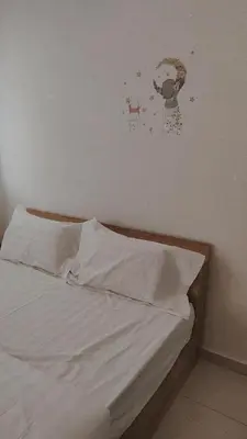 a bed with white sheets and a painting on the wall at Gopeng Serumah Holiday House in Gopeng