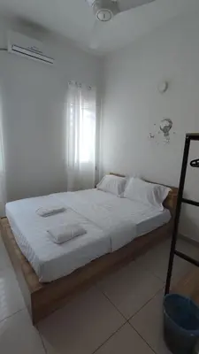 a bed with white sheets and pillows in a room at Gopeng Serumah Holiday House in Gopeng