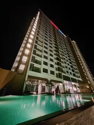 a tall building with a swimming pool at night at Cozy Suite with 270 Degree Mountain and Theme Park Views in Ipoh
