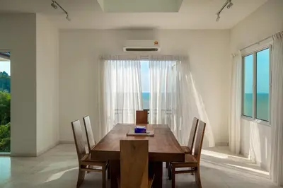 a dining room with a wooden table and a large window at Panoramic Seaview Holiday Home - Batu Ferringhi in Batu Ferringhi