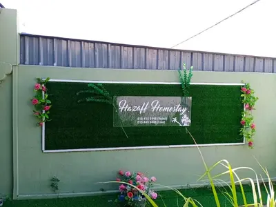 a sign on the side of a fence with flowers at Hazaff Homestay in Sungai Petani