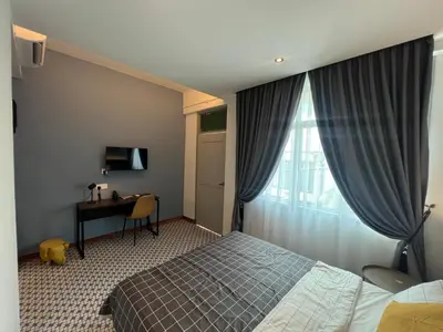 a bedroom with a bed and a desk and a window at Ninety Guest House in Ipoh