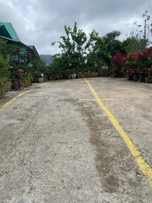 an empty parking lot next to a building with flowers at New Farmer Hut 1 in Brinchang
