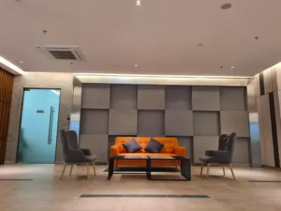 an orange couch in a lobby with two chairs at Sunway Onsen Suite Tambun Ipoh Mountain View in Ipoh