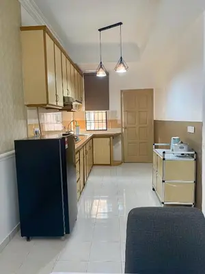 a large kitchen with a black refrigerator and cabinets at Comfy Sutera Seberang Jaya in Kampong Belah Dua