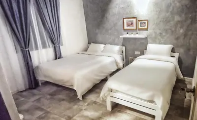 two beds in a room with white sheets at IPOH AGONG HOMESTAY by ONE LIFE FOUR SEASON GUESTHOUSE in Ipoh