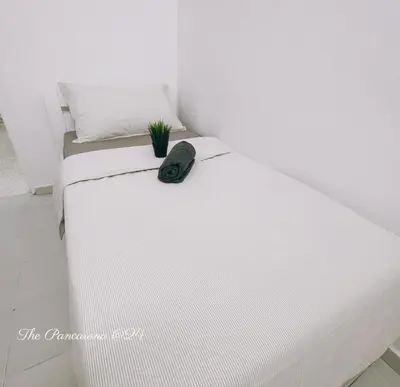 a white bed with a black hat on top of it at The Pancarona24 Homestay forMuslim in Ipoh