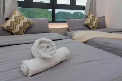 a bed with a white towel on top of it at Ipoh Tambun Lost World Sunway Onsen Suite 2R 8Pax Mira Theme Park View in Ipoh