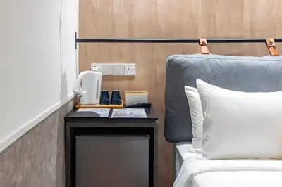 a bedroom with a bed and a nightstand with a phone at Bagan Suite in Butterworth