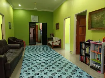 a living room with green walls and a couch and a rug at HOMESTAY JANNATI TAMBUN in Tambun