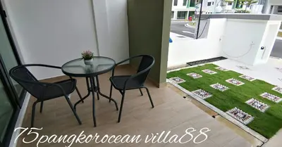 a table and chairs in a room with a green rug at 75 pangkor ocean in Pangkor