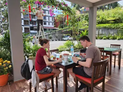 a man and woman sitting at a table in a restaurant at Fathers Guesthouse Age 7 years old and above only in Tanah Rata