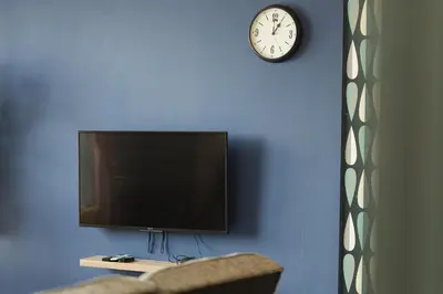 a living room with a tv and a clock on the wall at The CEDAR, 2BR Cityview by WStay @ Tropicana 218 Macalister in George Town