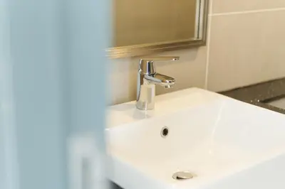 a bathroom sink with a faucet and a mirror at The CEDAR, 2BR Cityview by WStay @ Tropicana 218 Macalister in George Town