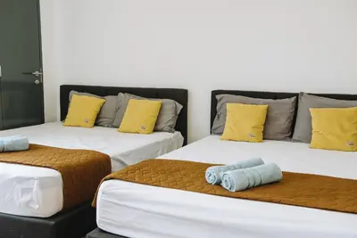 two beds in a room with yellow and blue pillows at The WHITE, 2BR Cityview by WStay @ Tropicana 218 Macalister in George Town