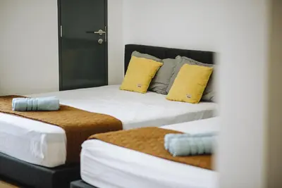 two beds with yellow and blue pillows in a room at The WHITE, 2BR Cityview by WStay @ Tropicana 218 Macalister in George Town
