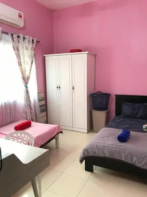 a bedroom with pink walls and two beds and a cabinet at Fidaiy Homestay in Teronoh