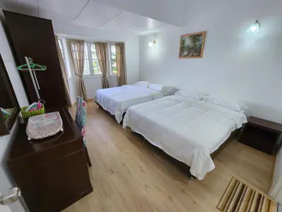 a bedroom with two beds and a table with a dresser at Little England B3 in Bukit Fraser