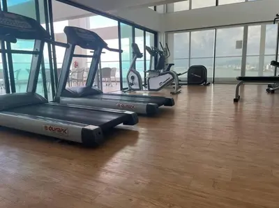 a gym with several cardio machines in a room with windows at Sunrise@Gurney Spacious 2BR Duplex in George Town
