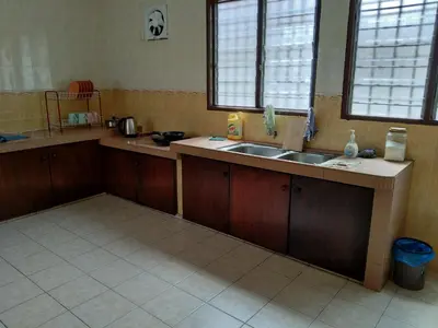 a kitchen with wooden cabinets and a sink and two windows at QQ Homestay in Ipoh