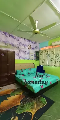 a bedroom with a bed in a room with a fan at Nur's Homestay in Seri Manjung