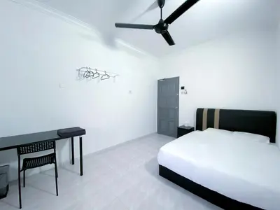 a bedroom with a bed and a desk and a ceiling fan at Venice Guest Hostel - Bilik Sahaja in Lumut