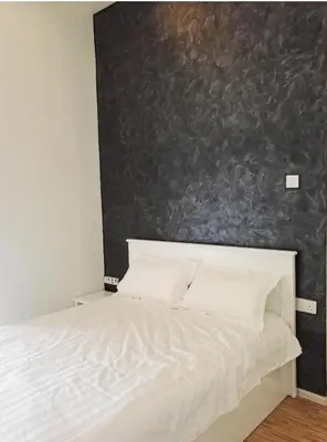 a bedroom with a white bed with a black wall at Cameron Lovely Home 3 Rooms in Tanah Rata
