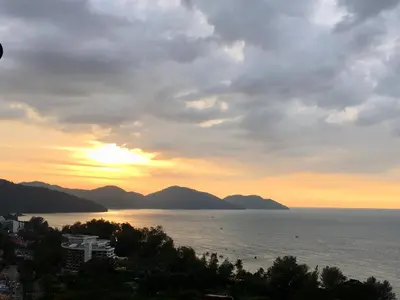 a sunset over the water with mountains in the background at The Ferringhi Sea View 777 in Batu Ferringhi