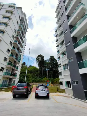 two cars parked in a parking lot next to tall buildings at Cameron Lovely Cottage 3 Rooms in Tanah Rata