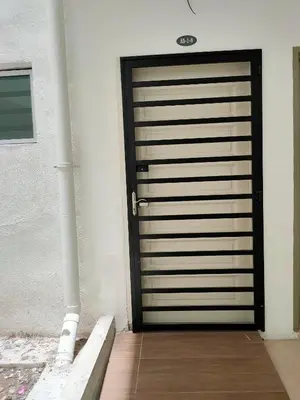 a black garage door in a white building at Cameron Lovely Cottage 3 Rooms in Tanah Rata