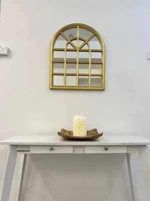 a table with a hat and a mirror on a wall at Roemah lily studio in Tanah Rata