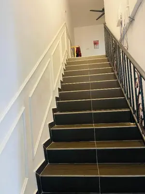 a staircase with black and wooden floors and white walls at NO 121 NAZIRIN HOMESTAY TMN DESA MANJUNG in Lumut
