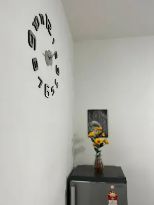 a clock on a wall with a vase on a refrigerator at Izwana Muslim Homestay in Tanah Rata