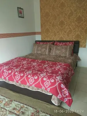 a bedroom with a bed with a red comforter at Emily Homestay Cameron Highlands in Tanah Rata