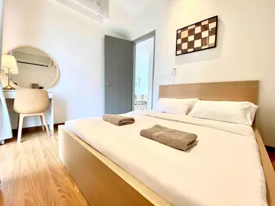a large white bed in a room with a chair at Beacon Executive Suites #Warmth #SkyPool #Georgetown #5pax #2BR 2bath #2Queen 1Single #Quality well maintained #Private host in George Town