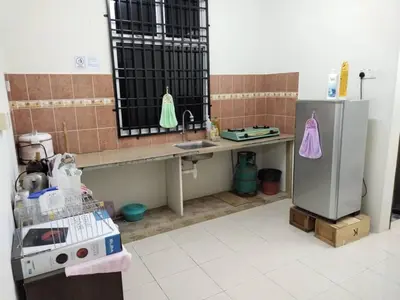 a kitchen with a counter and a sink and a refrigerator at Permai Homestay in Baling