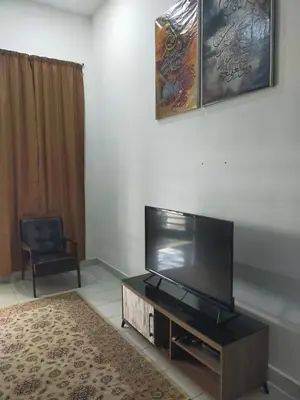 a living room with a flat screen tv and a chair at Kerian Putra Muslimstay in Parit Buntar