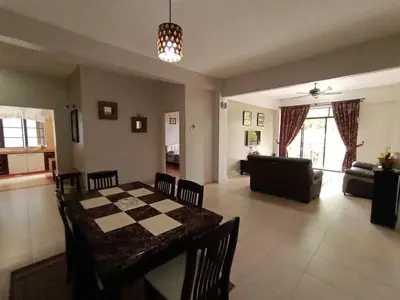 a dining room and living room with a table and chairs at Aspen Holiday Apartment in Tanah Rata