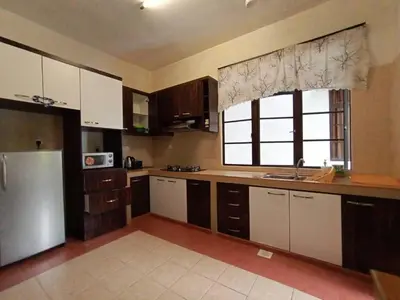 a kitchen with white cabinets and a refrigerator and a window at Aspen Holiday Apartment in Tanah Rata