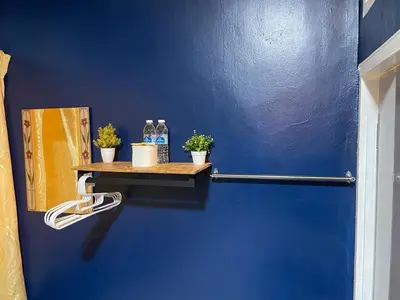 a blue wall with bottles of water and potted plants on a shelf at Vintage Guesthouse in Tanah Rata