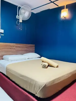 a bedroom with a bed with a blue wall and a fan at Vintage Guesthouse in Tanah Rata