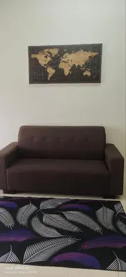 a brown couch in a room with a map on the wall at Homestay Lumut Perak 2026 in Lumut