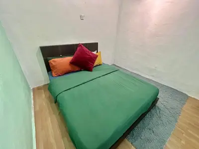 a green bed with two colorful pillows on it at Cozy18#4pax#NearAeonAlma,Mcd#2kmtoIconic in Bukit Mertajam